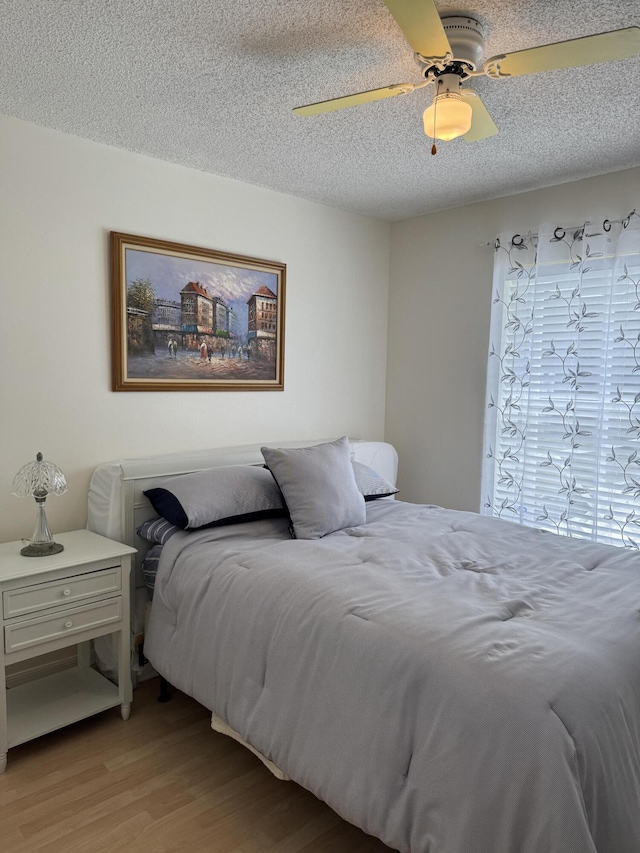 bedroom with light wood-style floors, a textured ceiling, and a ceiling fan