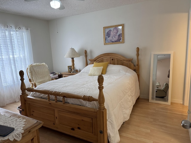 bedroom featuring a textured ceiling, ceiling fan, light wood finished floors, and multiple windows