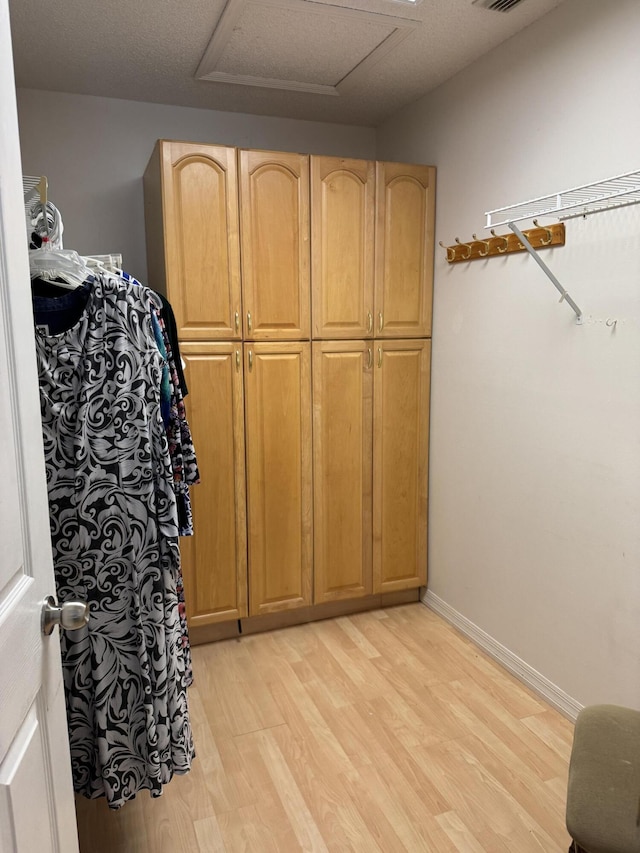 spacious closet with light wood-style flooring and attic access