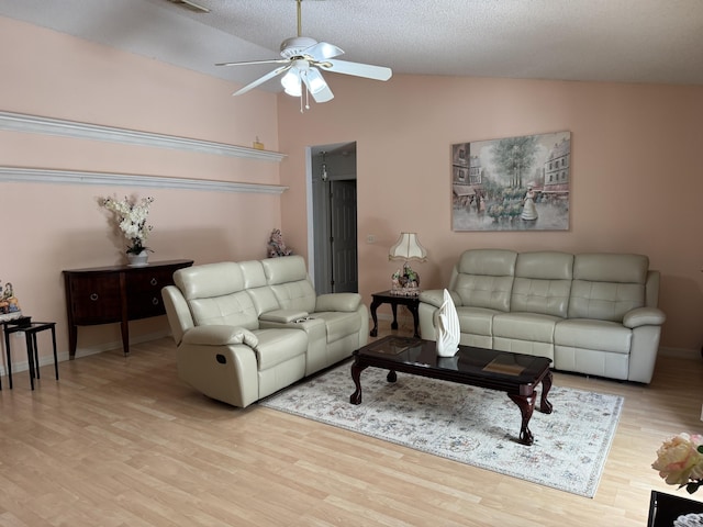 living room with ceiling fan, a textured ceiling, baseboards, vaulted ceiling, and light wood-type flooring