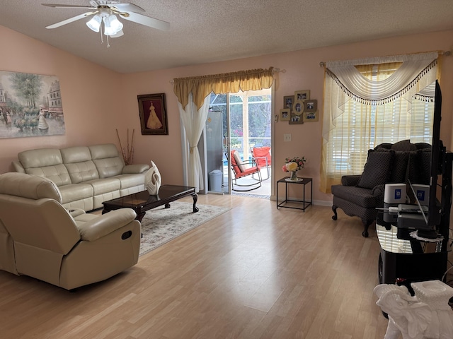 living room featuring light wood-style floors, vaulted ceiling, a textured ceiling, and a ceiling fan