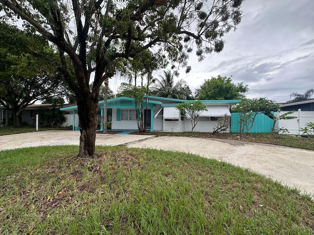 view of front of house with driveway, a front yard, and fence