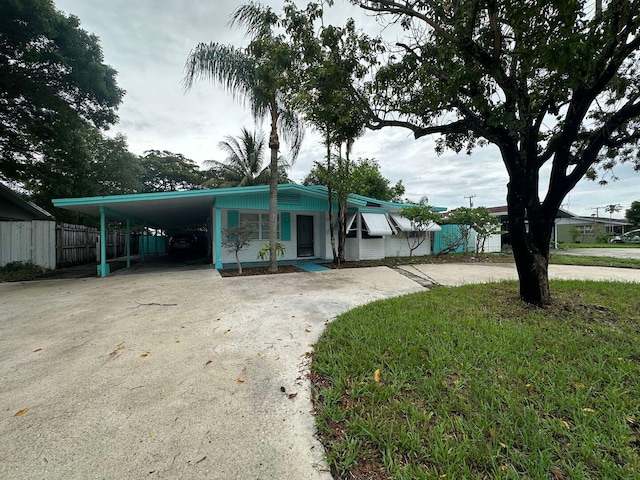 view of front of property featuring driveway, fence, and a carport