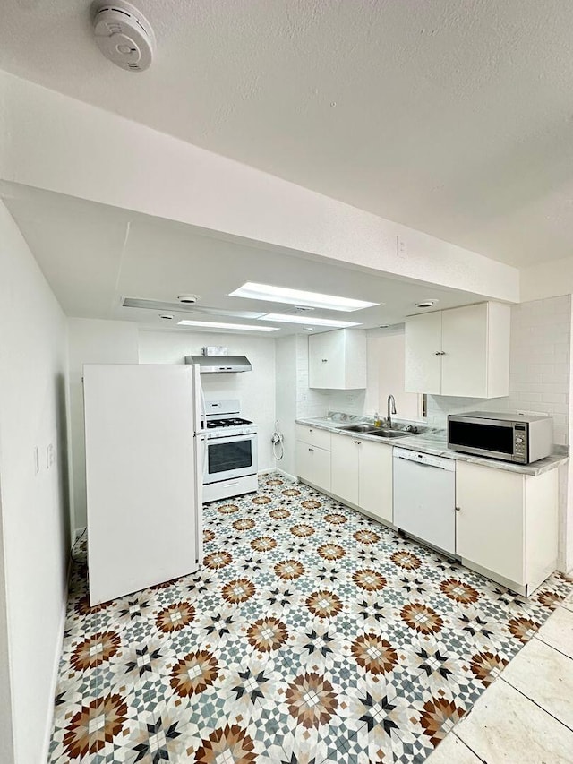 kitchen featuring white appliances, light countertops, a textured ceiling, white cabinetry, and a sink