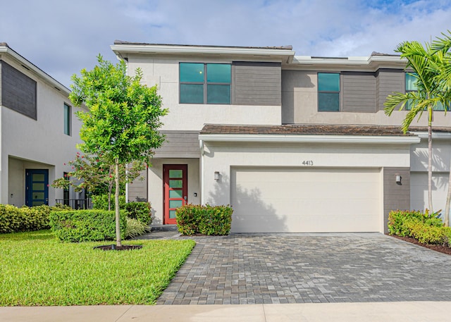 view of front of house featuring a garage, a front yard, decorative driveway, and stucco siding