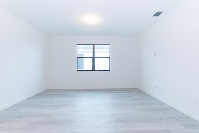 unfurnished room featuring light wood finished floors, visible vents, and baseboards