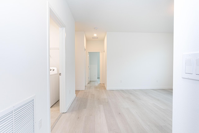 empty room with washer / dryer, light wood-style flooring, and baseboards