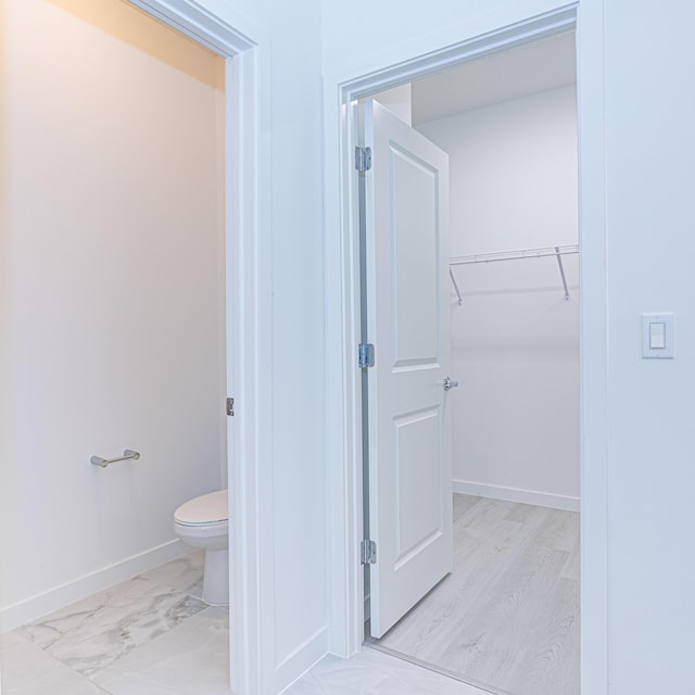 bathroom featuring marble finish floor, toilet, and baseboards