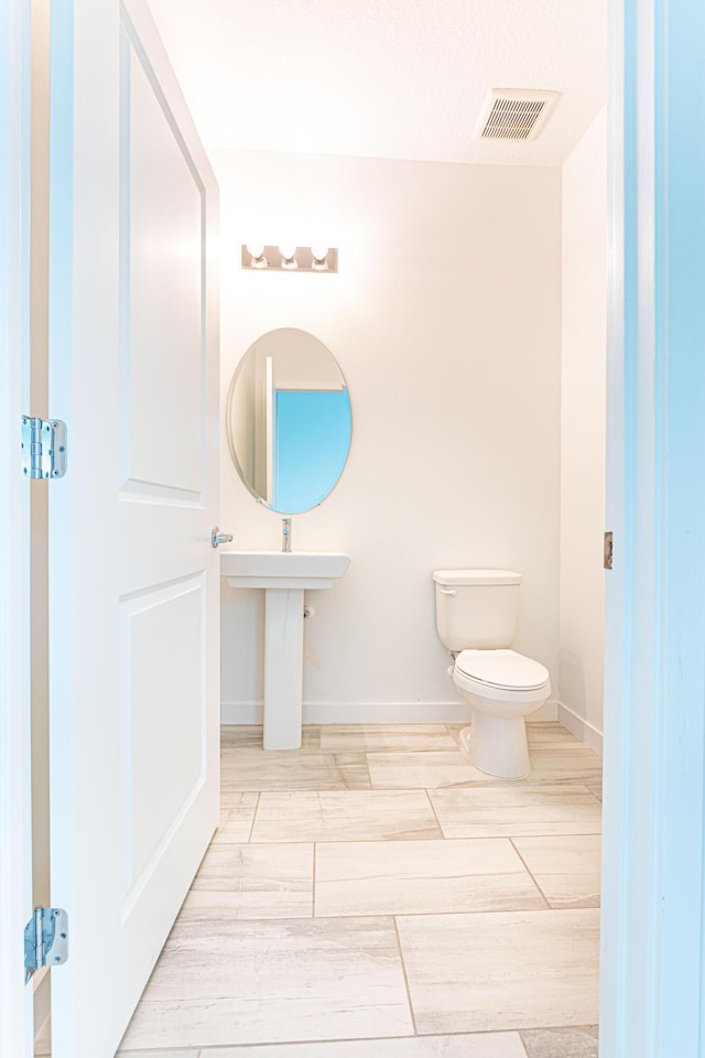 bathroom featuring toilet, baseboards, visible vents, and wood finish floors