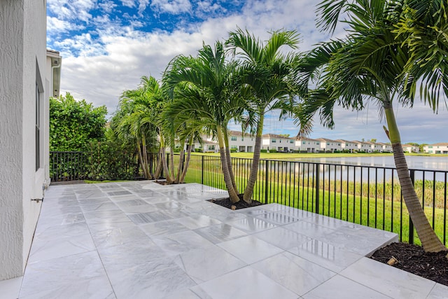 view of patio with a water view, fence, and a residential view