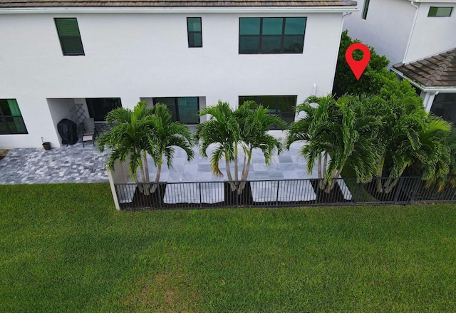 back of property with fence, a yard, a patio, and stucco siding