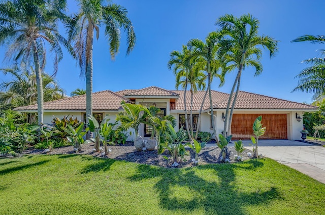 mediterranean / spanish home featuring a garage, concrete driveway, a front lawn, and stucco siding