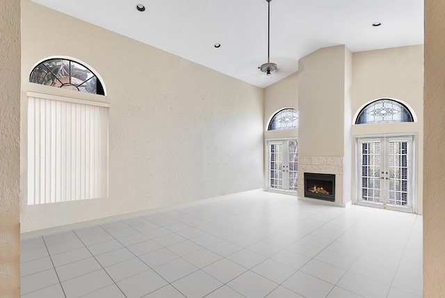 unfurnished living room with french doors, high vaulted ceiling, a fireplace, and a textured wall