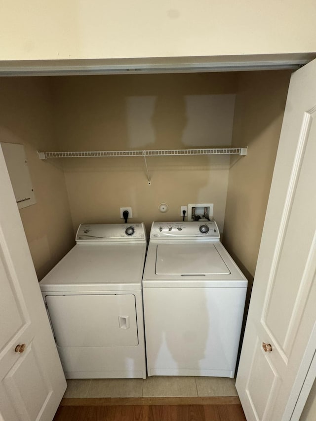 laundry area with light wood-type flooring, washing machine and dryer, and laundry area