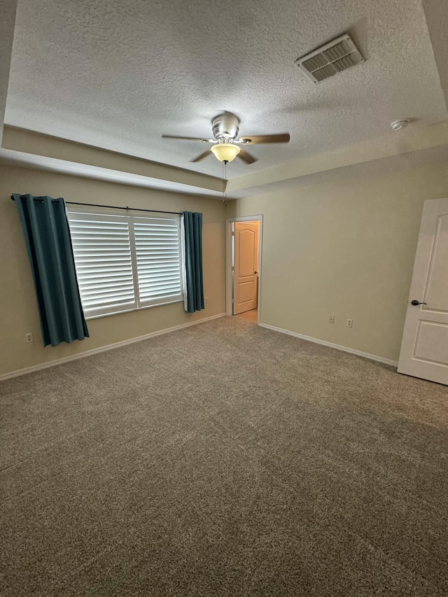 spare room with a ceiling fan, visible vents, carpet floors, baseboards, and a textured ceiling