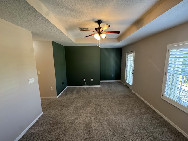 carpeted spare room featuring a healthy amount of sunlight, baseboards, and a tray ceiling