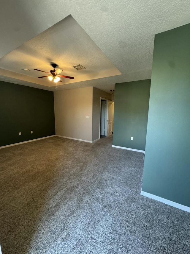 carpeted spare room featuring visible vents, a raised ceiling, a textured ceiling, baseboards, and ceiling fan