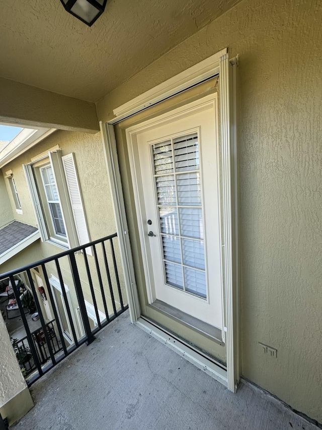 view of exterior entry with stucco siding and a balcony