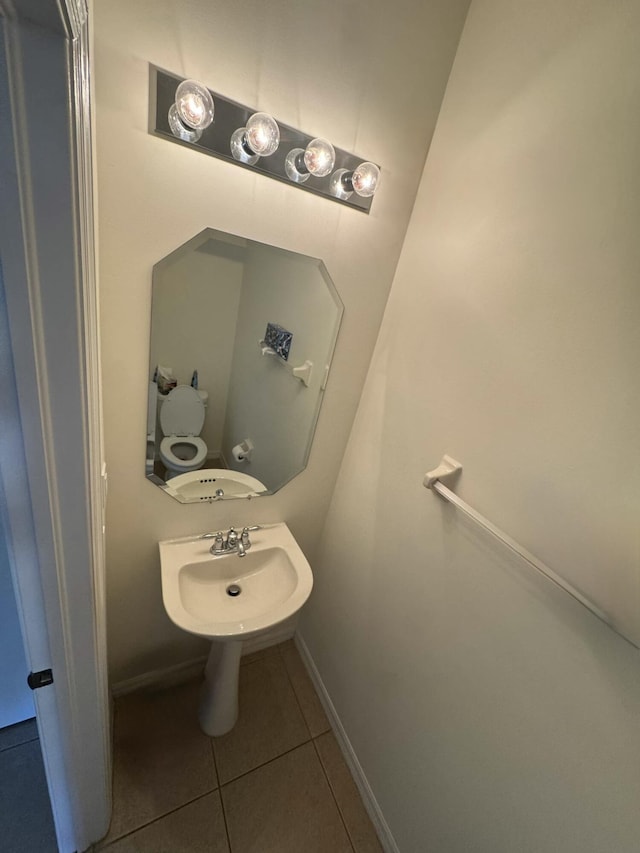 bathroom with a sink, baseboards, toilet, and tile patterned flooring