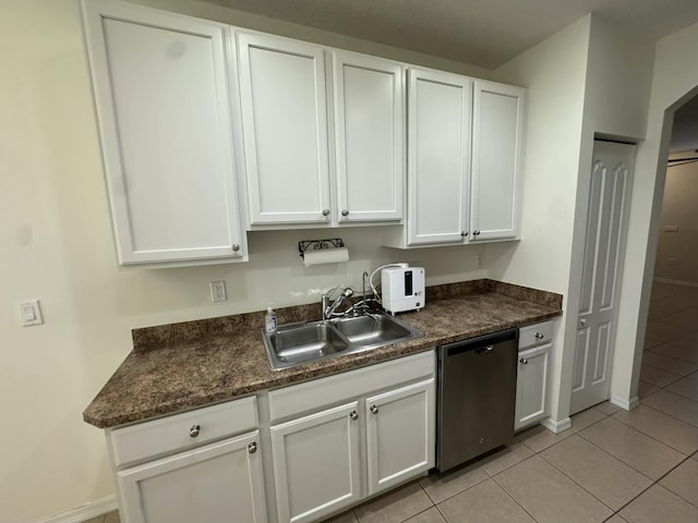 kitchen with dark countertops, light tile patterned floors, dishwasher, and a sink