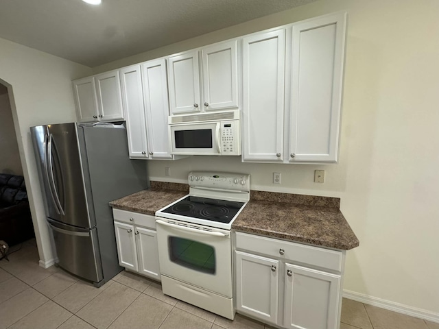 kitchen featuring light tile patterned flooring, white appliances, white cabinetry, and baseboards