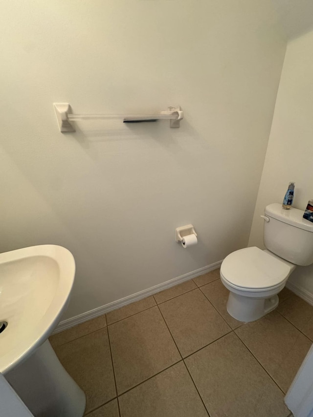 half bathroom featuring tile patterned flooring, toilet, and baseboards