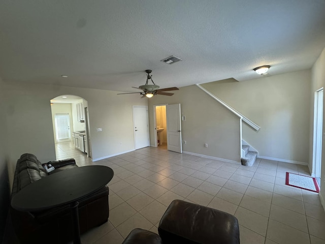 living area featuring visible vents, stairway, light tile patterned floors, arched walkways, and a textured ceiling