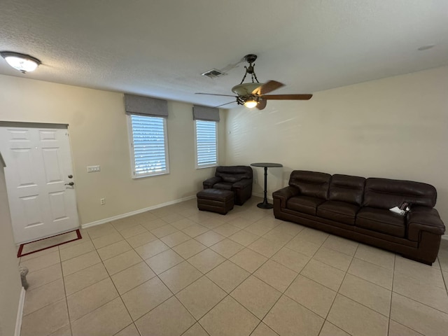 living area with visible vents, a ceiling fan, a textured ceiling, light tile patterned floors, and baseboards