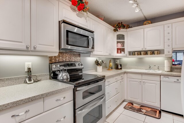 kitchen with light tile patterned floors, appliances with stainless steel finishes, light countertops, a textured ceiling, and white cabinetry