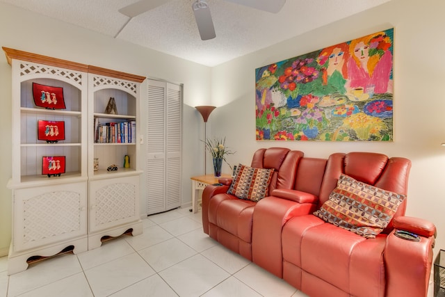 living area with a ceiling fan, tile patterned flooring, and a textured ceiling