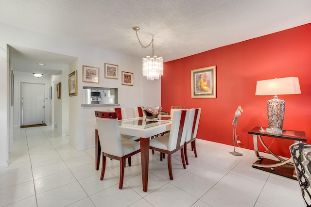 dining area featuring a chandelier, light tile patterned flooring, a textured ceiling, and baseboards