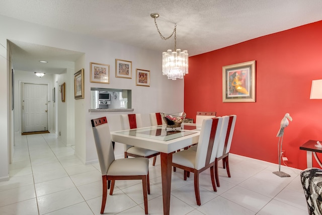 dining room with a textured ceiling, light tile patterned floors, baseboards, and a notable chandelier