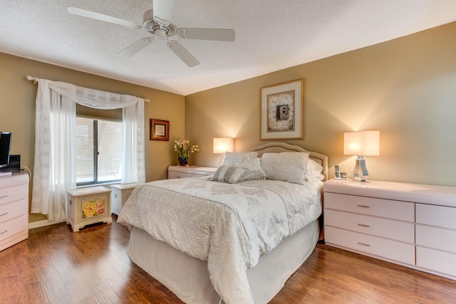 bedroom with a textured ceiling, ceiling fan, and wood finished floors