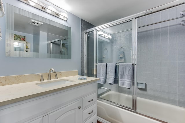 bathroom with bath / shower combo with glass door and vanity