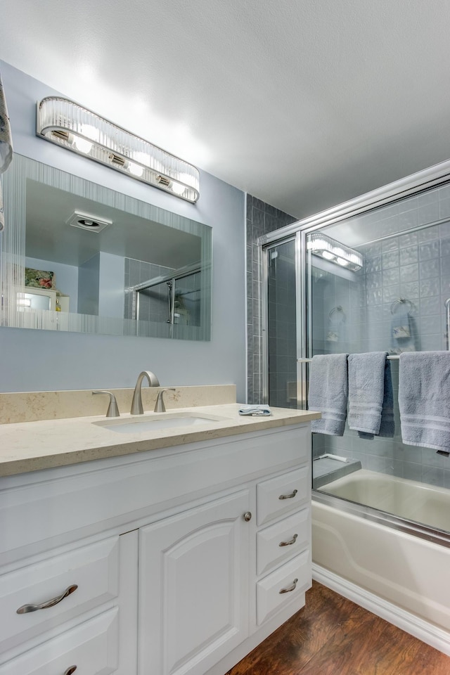 bathroom with combined bath / shower with glass door, wood finished floors, and vanity