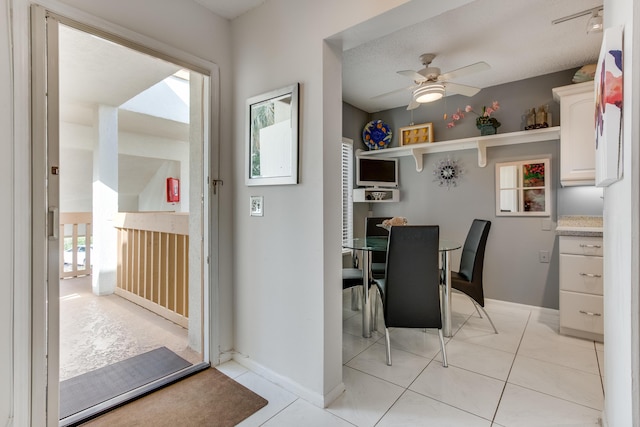 dining space with a ceiling fan, baseboards, and light tile patterned floors