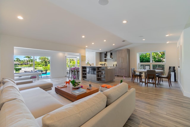 living room featuring recessed lighting, baseboards, light wood-style floors, and vaulted ceiling