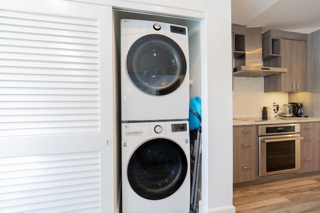 laundry room featuring laundry area, light wood-style floors, and stacked washer / drying machine