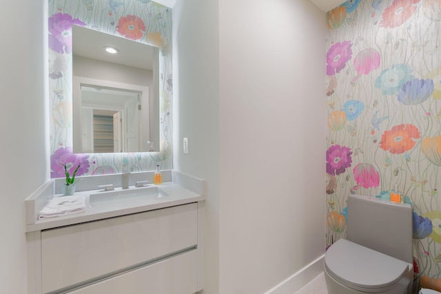 bathroom with baseboards, toilet, vanity, and wallpapered walls