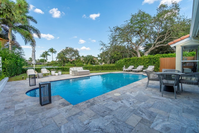 view of pool featuring a patio, outdoor dining area, fence, and a fenced in pool