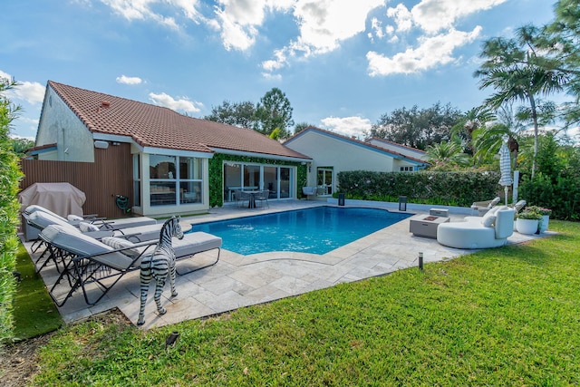 rear view of property with a fenced in pool, fence, a tile roof, a lawn, and a patio area