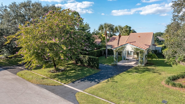 view of front of home with aphalt driveway, a tiled roof, and a front yard