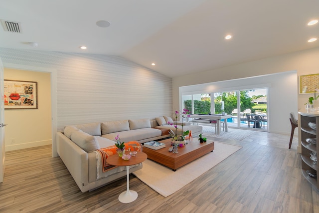 living area featuring vaulted ceiling, wood finished floors, visible vents, and baseboards