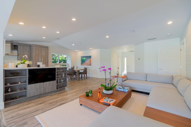 living room with lofted ceiling, recessed lighting, light wood-type flooring, and baseboards