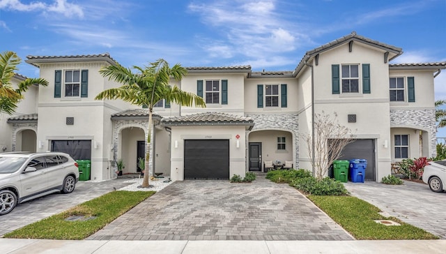 view of front of home featuring stucco siding, decorative driveway, and a garage