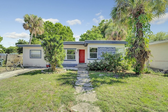 ranch-style home with a front yard, fence, and stucco siding