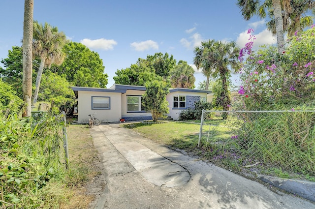 view of front of home with fence, a front lawn, and stucco siding