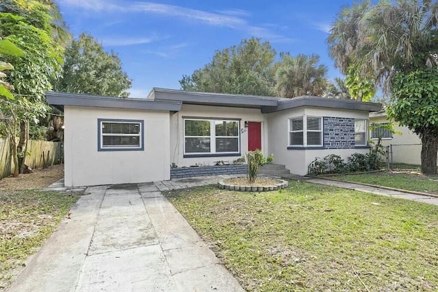 ranch-style house with fence, a front lawn, and stucco siding