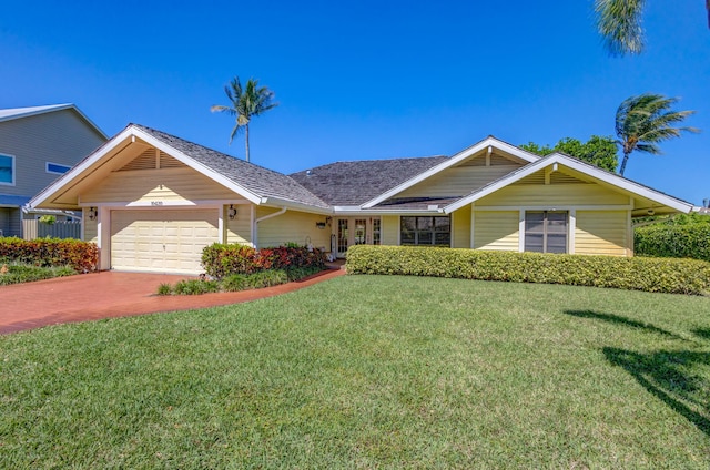 single story home with an attached garage, a front lawn, and decorative driveway