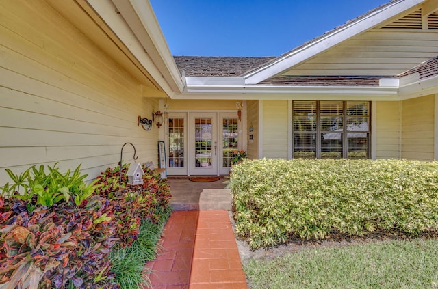 view of exterior entry with french doors and a shingled roof